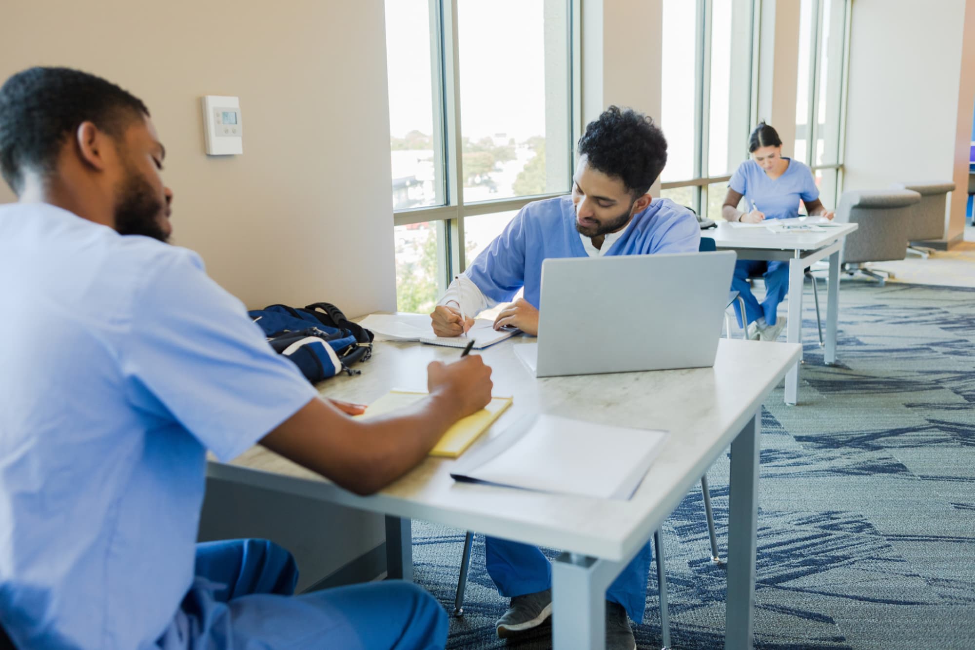 Nursing students taking notes and studying on laptops