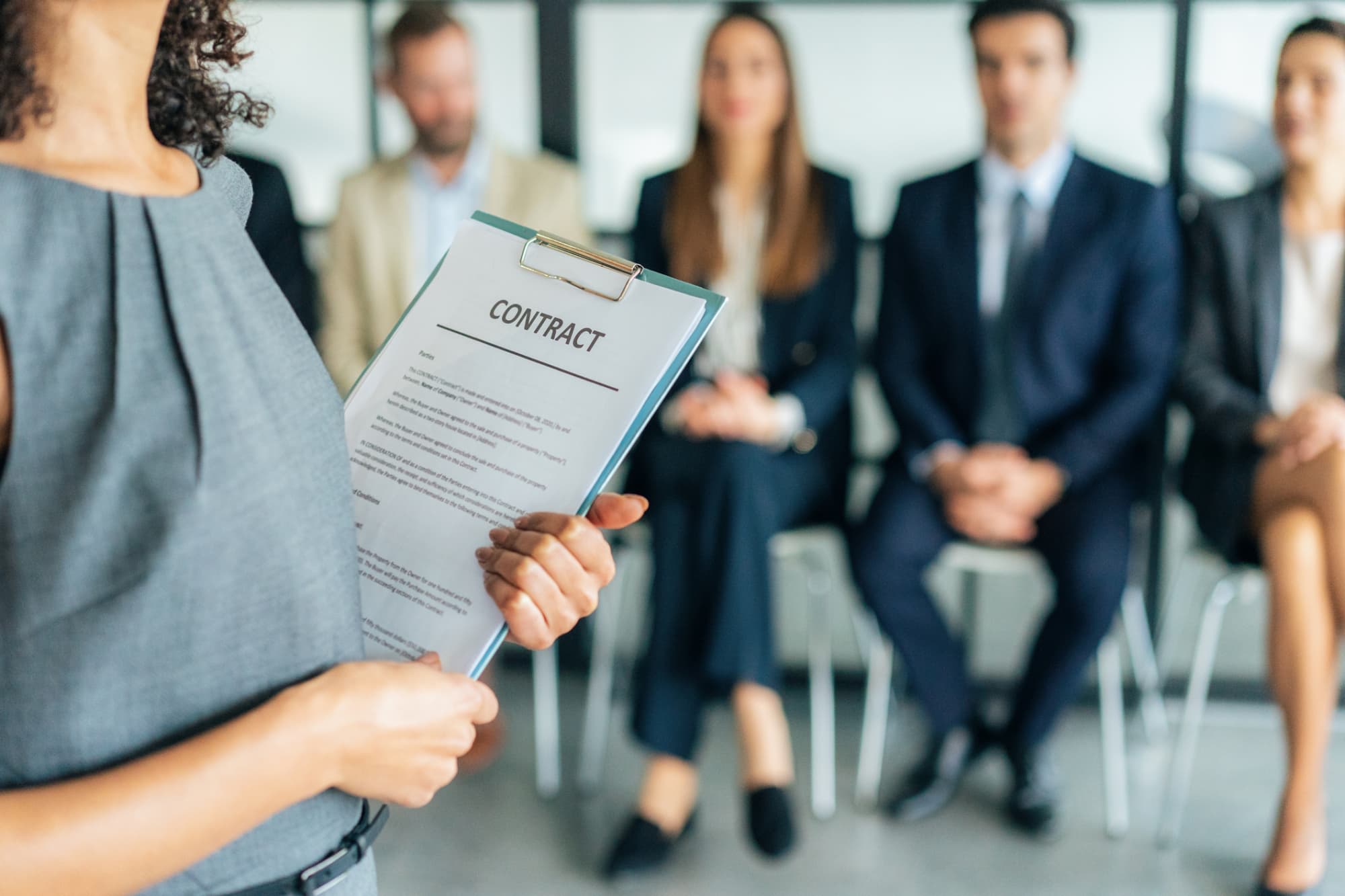 HR manager holding clipboard by seated employees