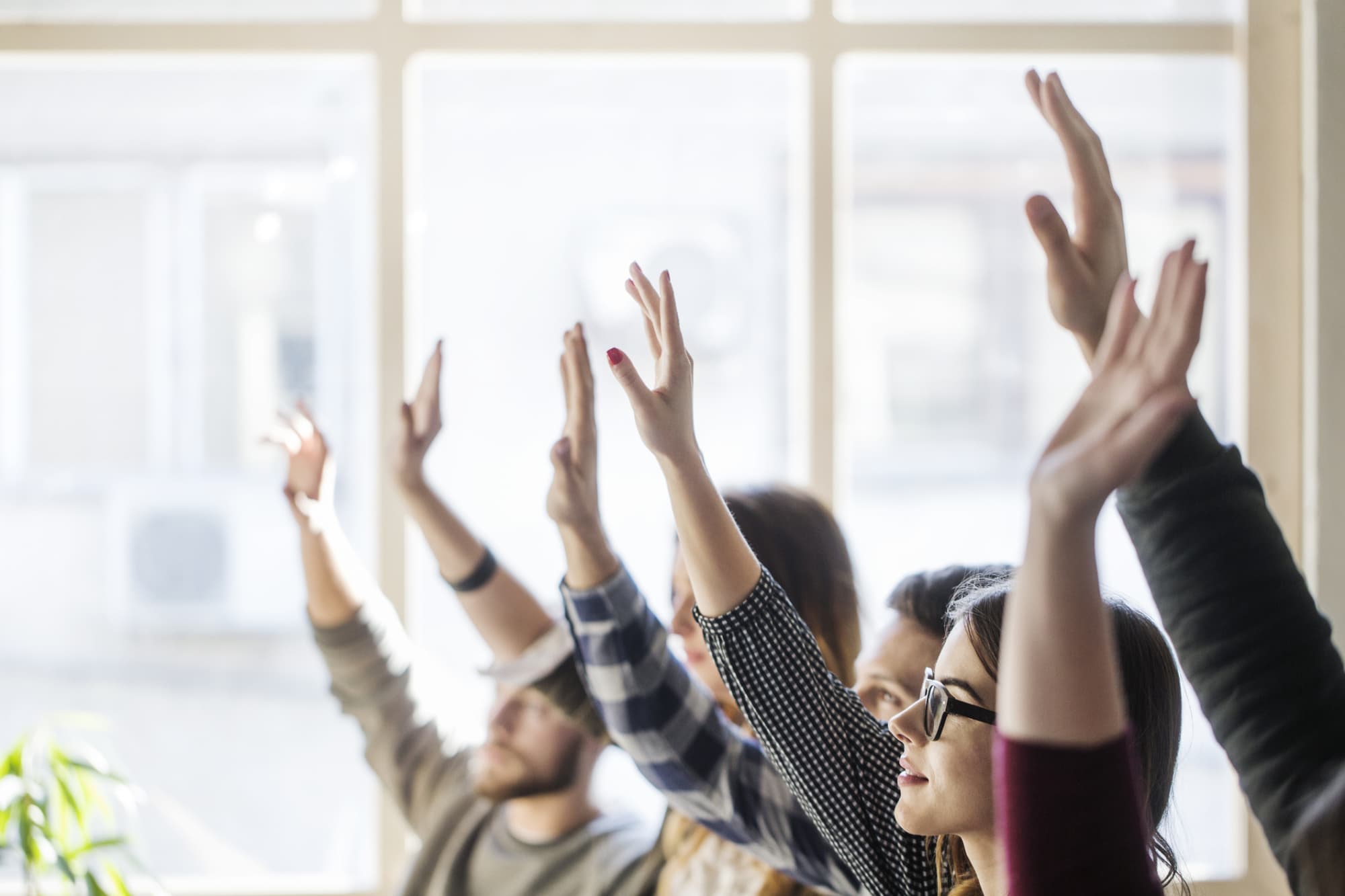 University students raising their hands in a classroom