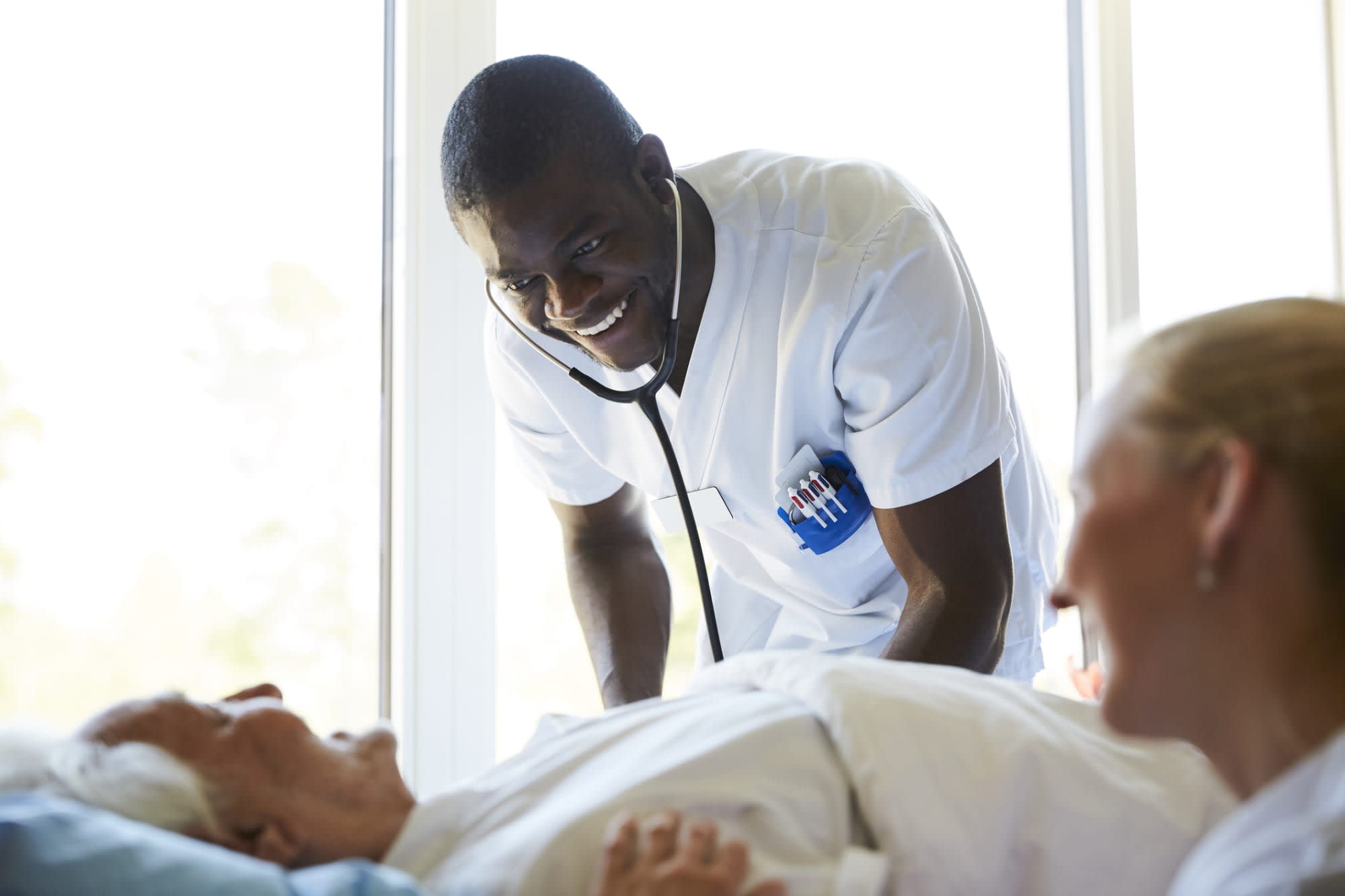 Nurses talking to a senior patient in bed