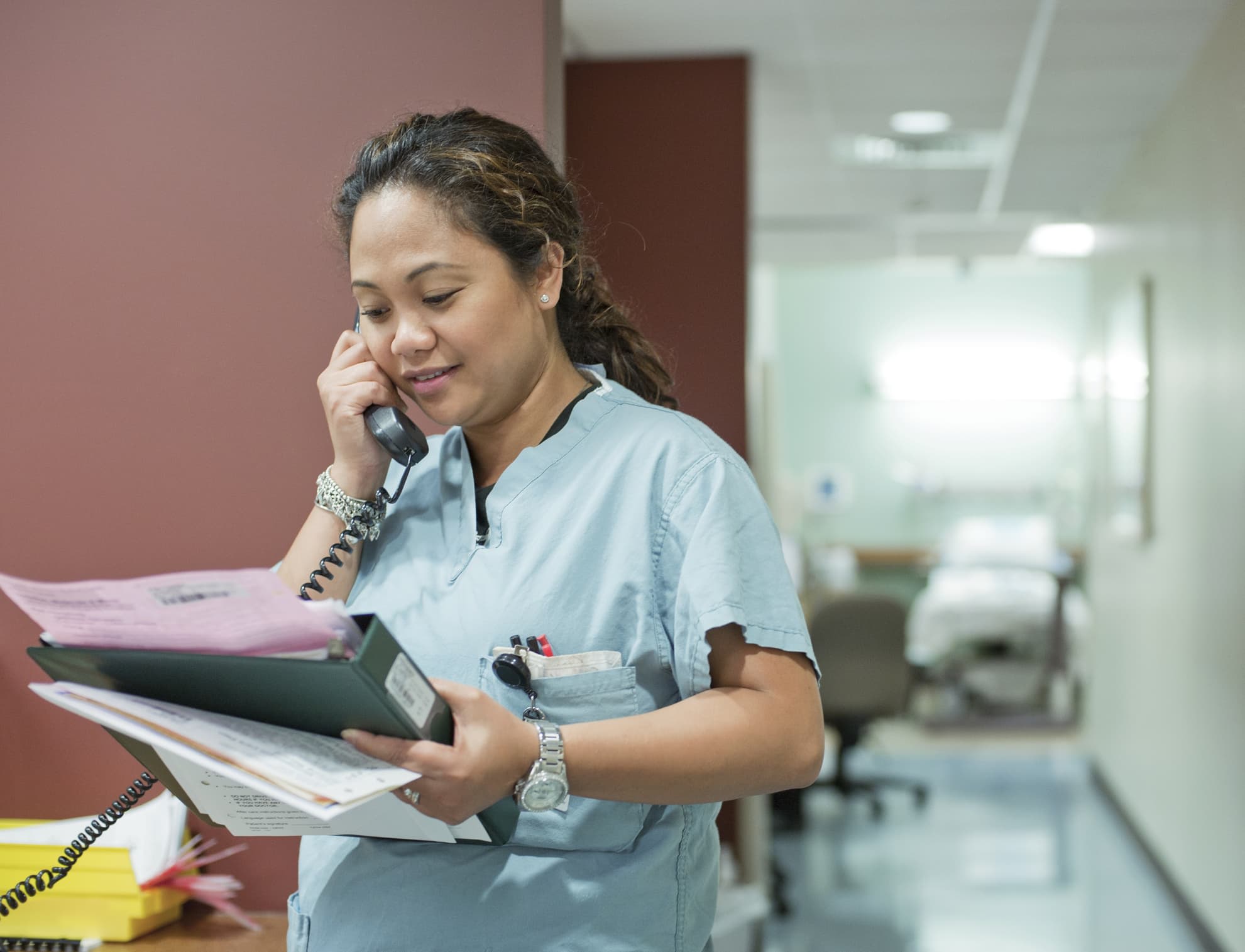 Nurse looking at chart and talking on telephone