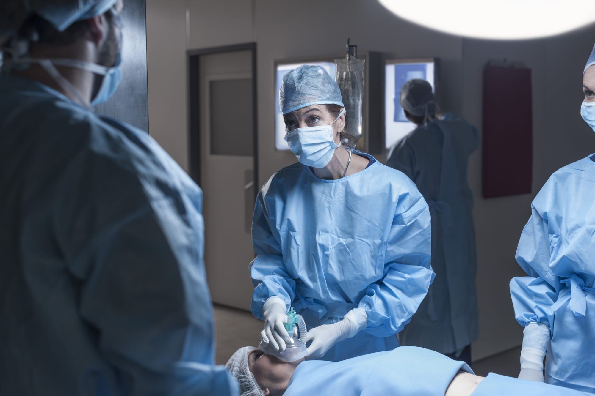 Nurse anesthetist administering medicine to patient in surgery room