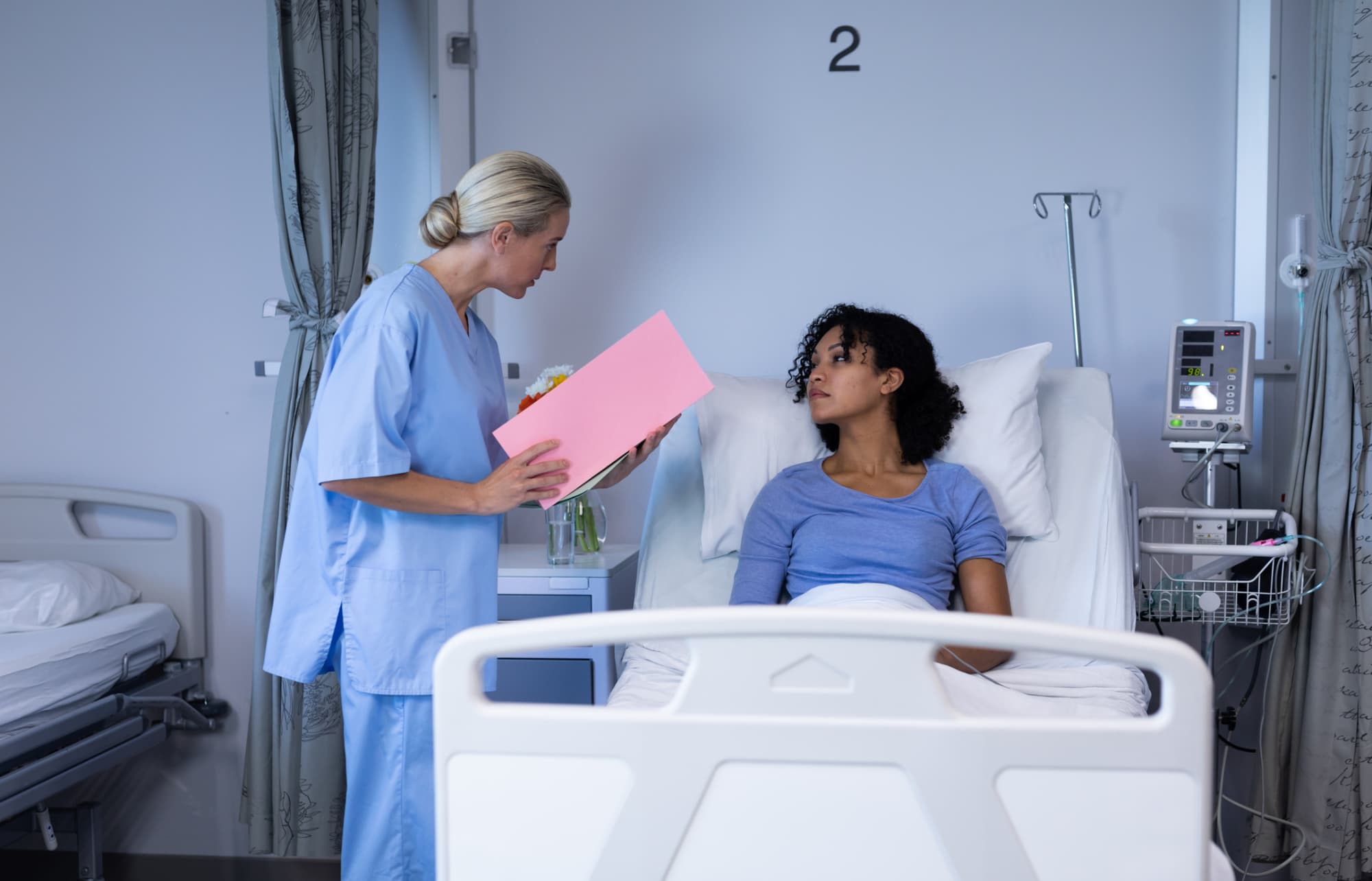 Travel nurse talking to patient in hospital bed