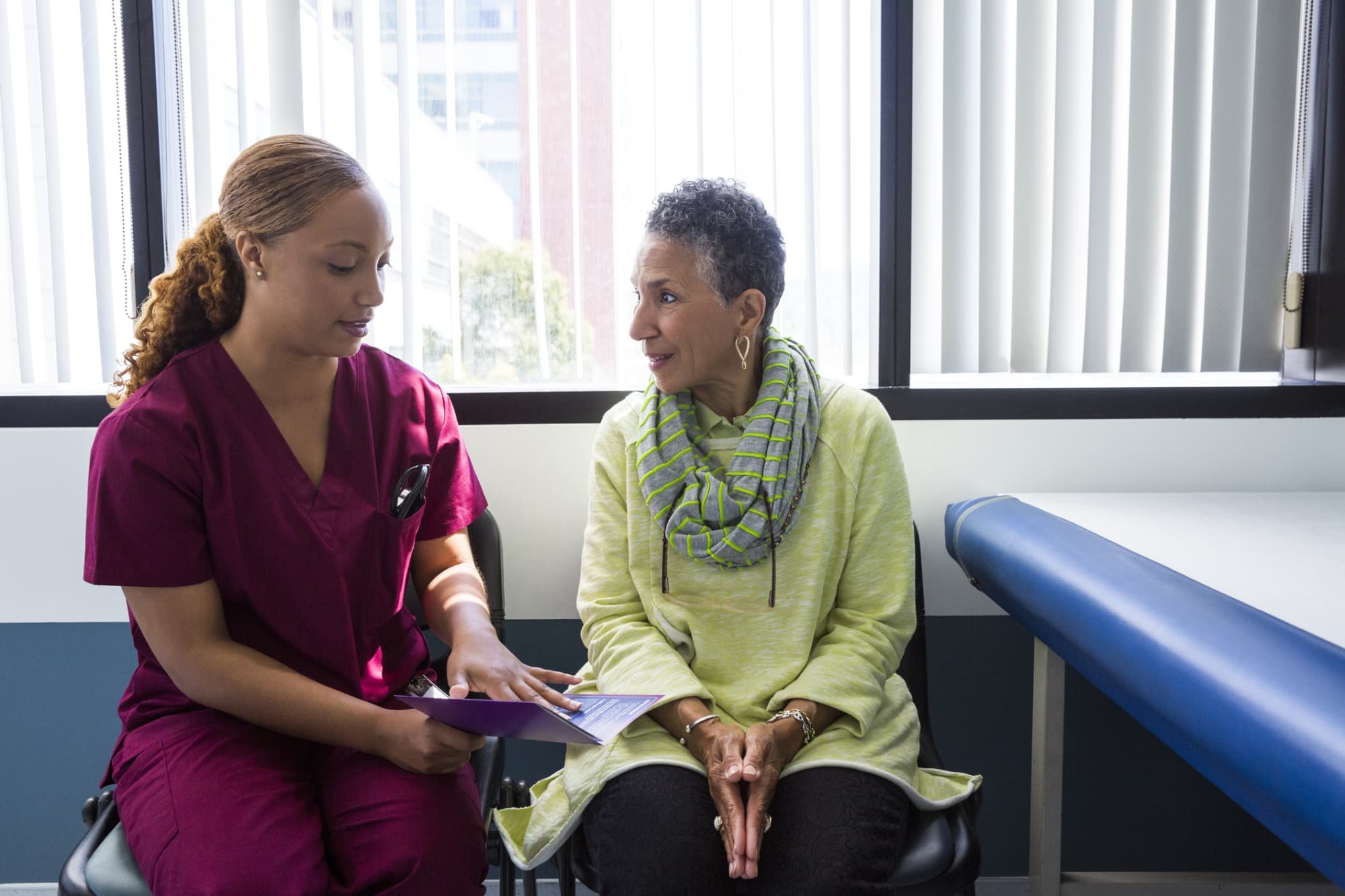 Black nurse talking to black patient