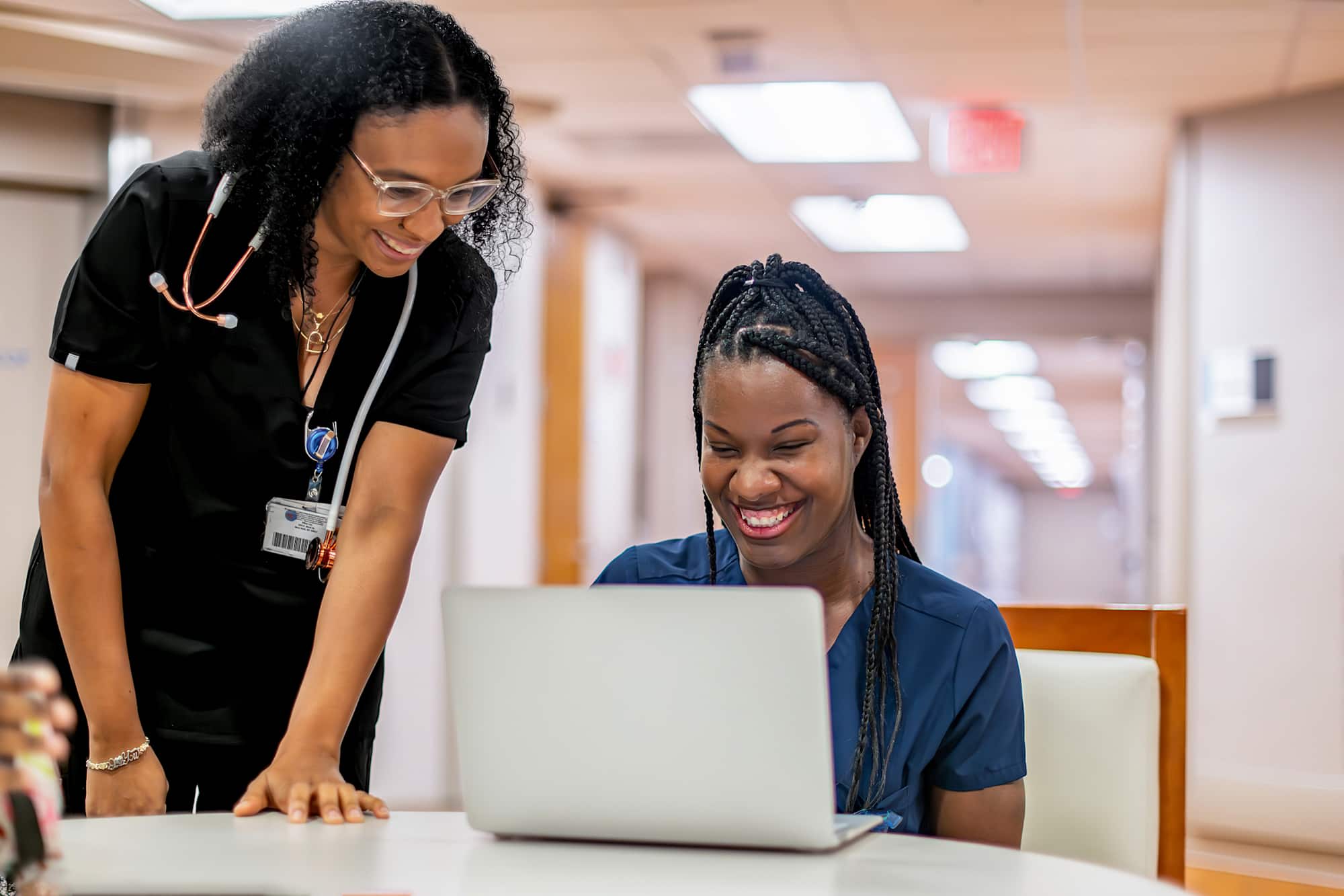 Nursing student on laptop getting help from nurse