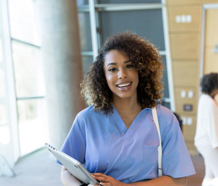 Nurse smiling and carrying laptop