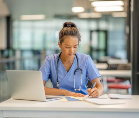 Nursing student studying on laptop in library