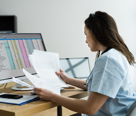 RN Coder looking at paperwork at computer desk