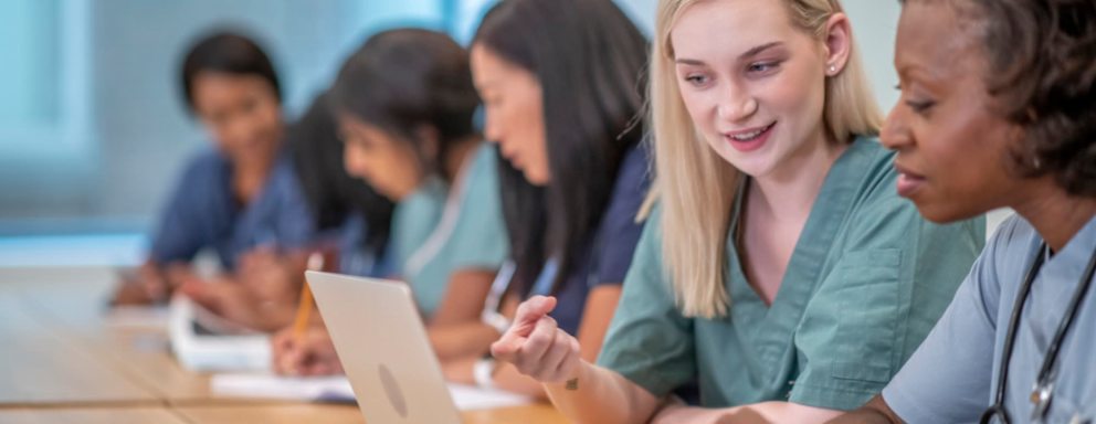 Nurses working on laptops together at a desk