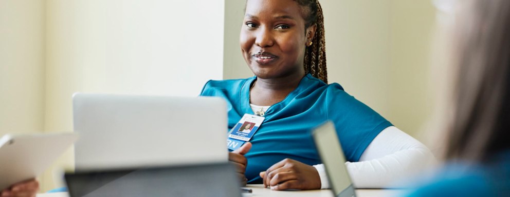 Nurse on laptop talking to other nurses