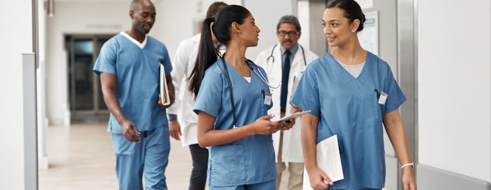 Team of doctors and nurses walking down a hospital hallway together