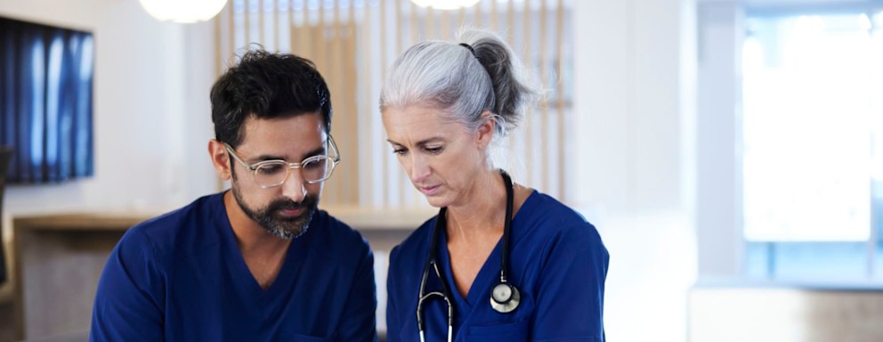 An older and younger nurse looking at a tablet together