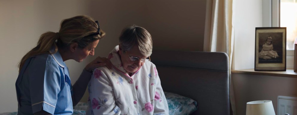 Nurse sitting with elderly patient on bed