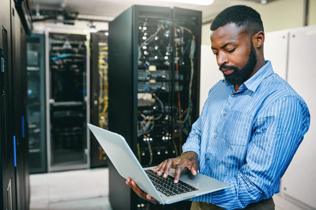 Man working on laptop in server room