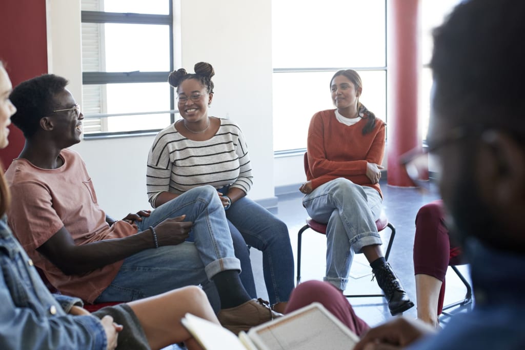 Black and African-American students sitting in a circle and having a discussion during a college mental health support group.