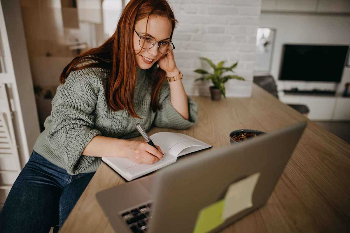 Female student working on laptop at home, typing on computer keyboard