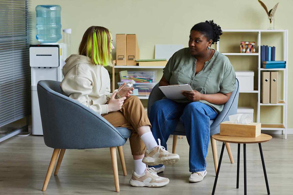 Woman psychologist talking to teenage girl at office