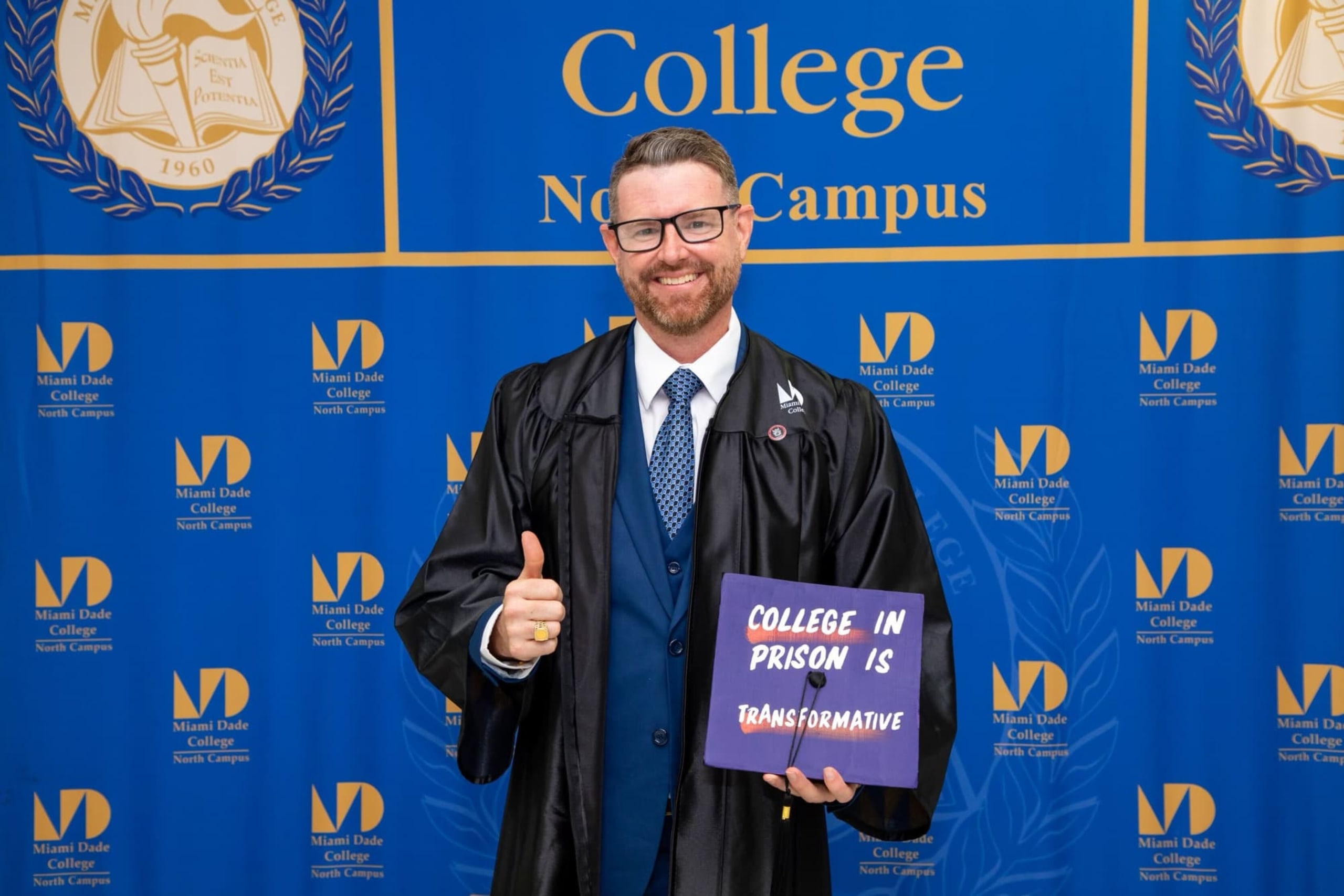 Larry Eddie Fordham smiles and gives a thumbs up while holding his degree at his graduation ceremony. His degree cover reads, College in prison is transformative.