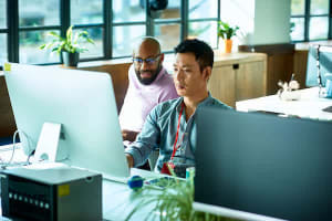 Man showing coworker how to code on his computer screen