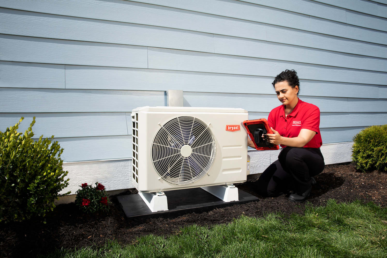 Bryant technician talking with homeowner while checking air filter and furnace