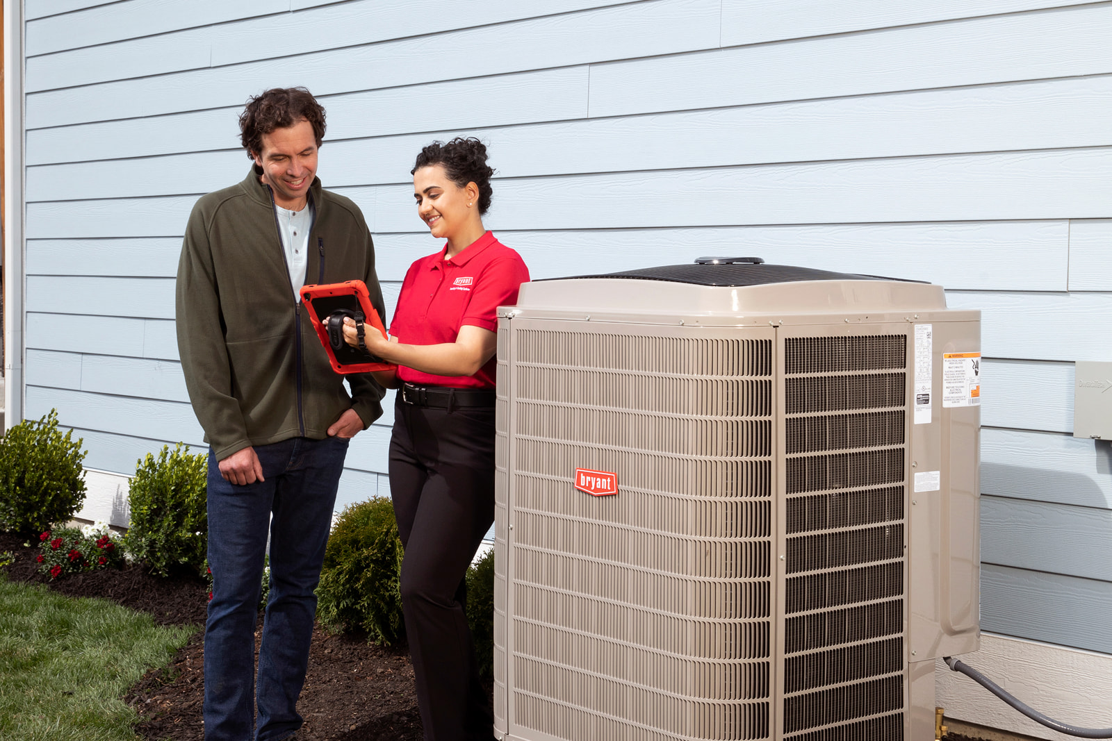 Bryant technician talking with homeowner while checking air filter and furnace