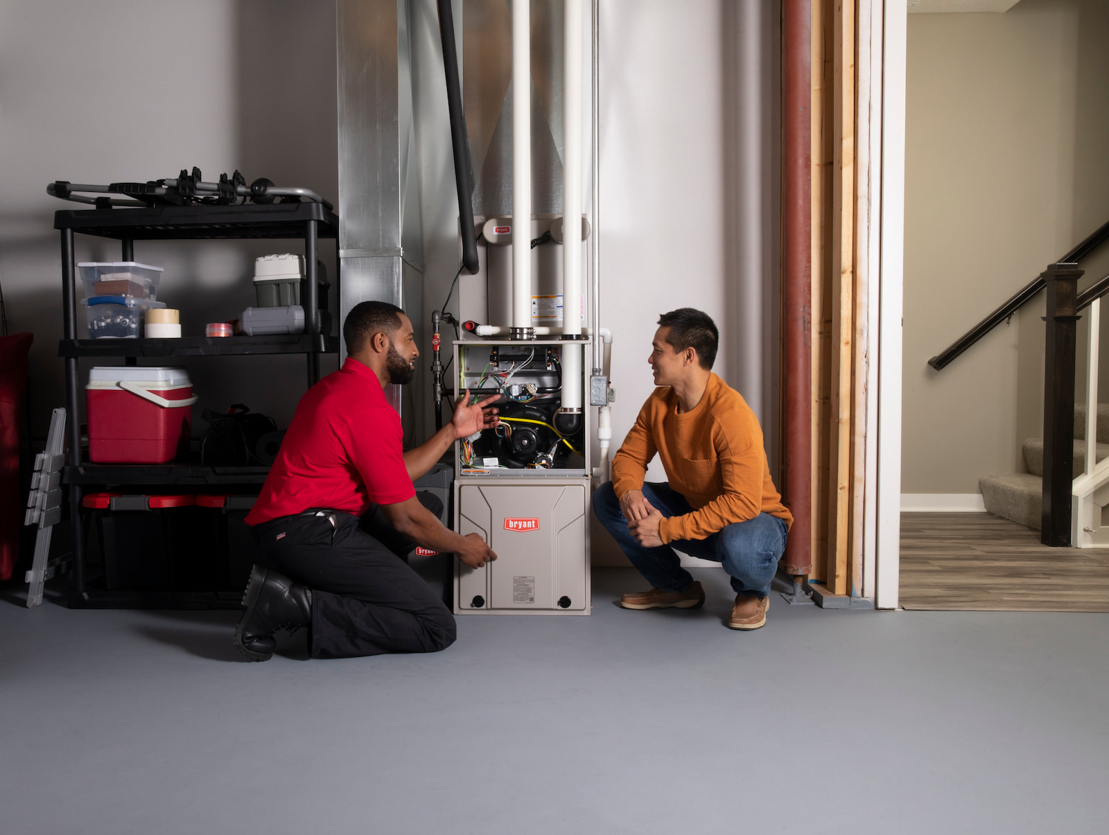 Bryant technician talking with homeowner while checking air filter and furnace