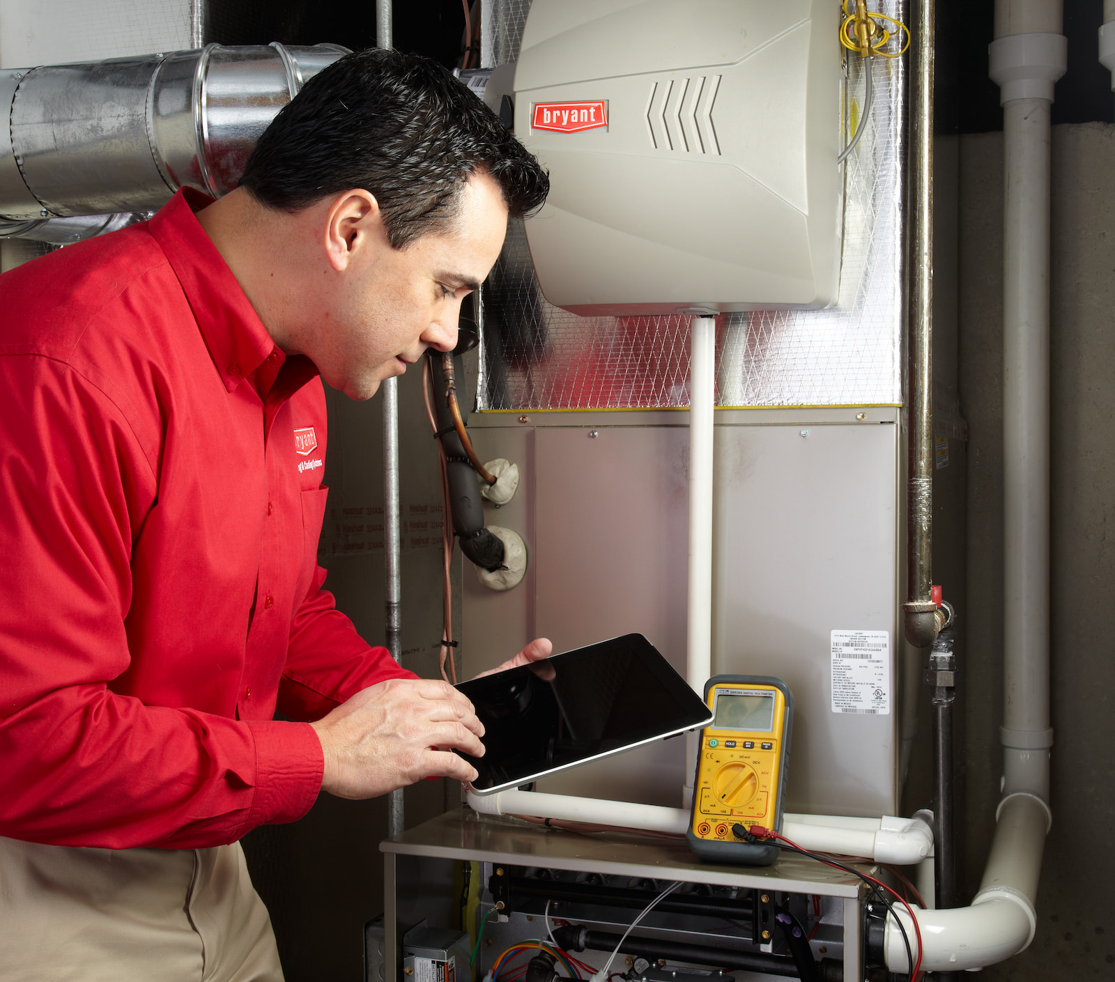 Bryant technician talking with homeowner while checking air filter and furnace