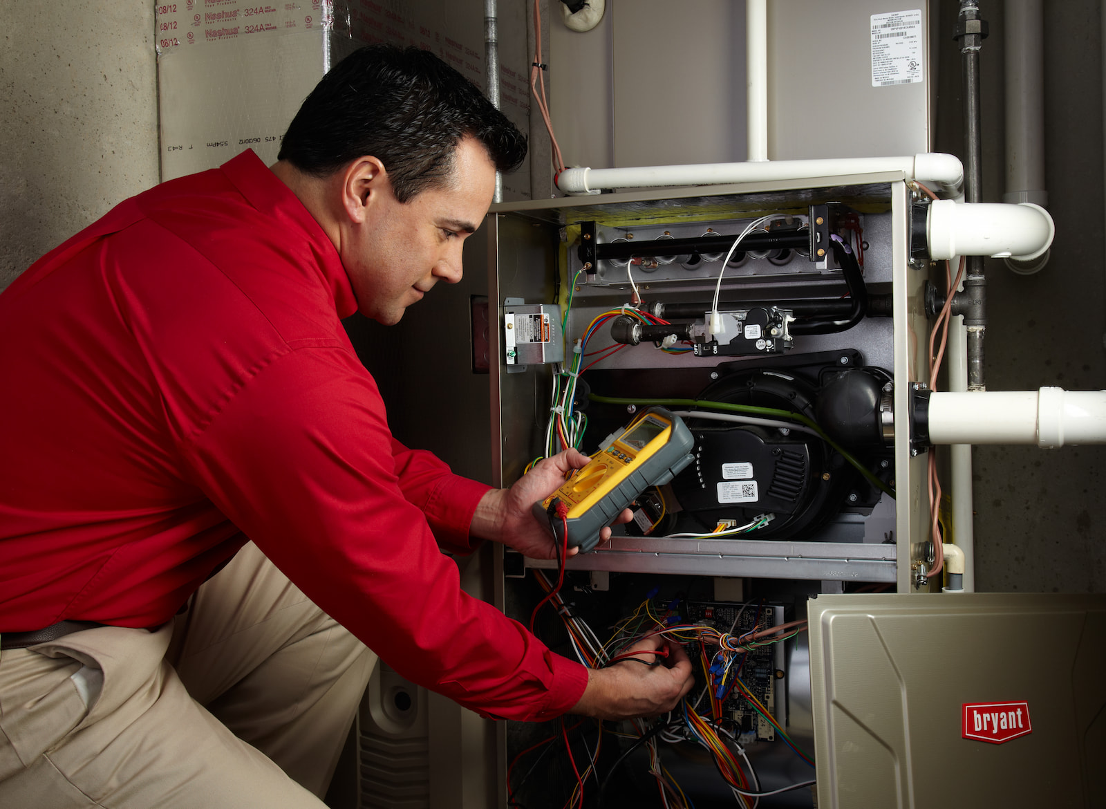 Bryant technician talking with homeowner while checking air filter and furnace