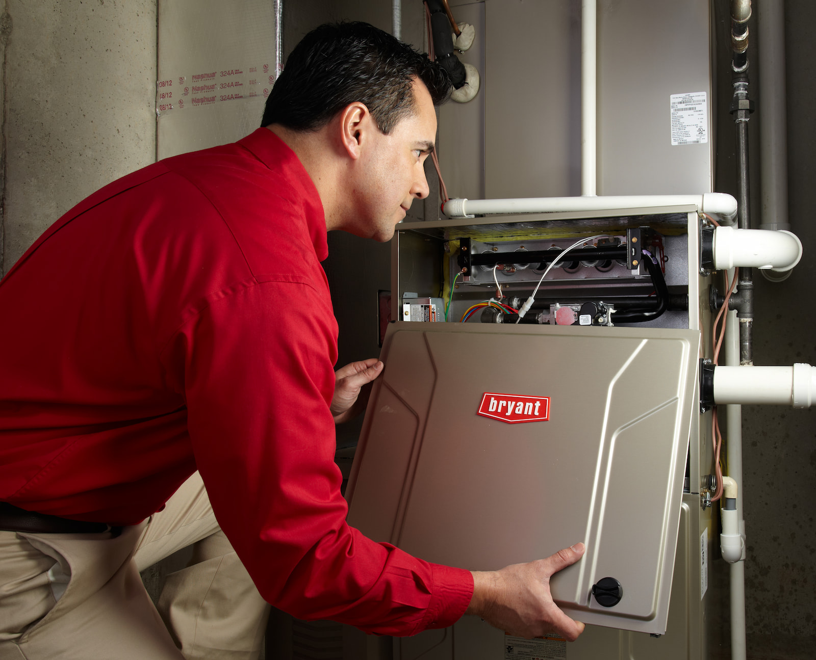 Bryant technician talking with homeowner while checking air filter and furnace