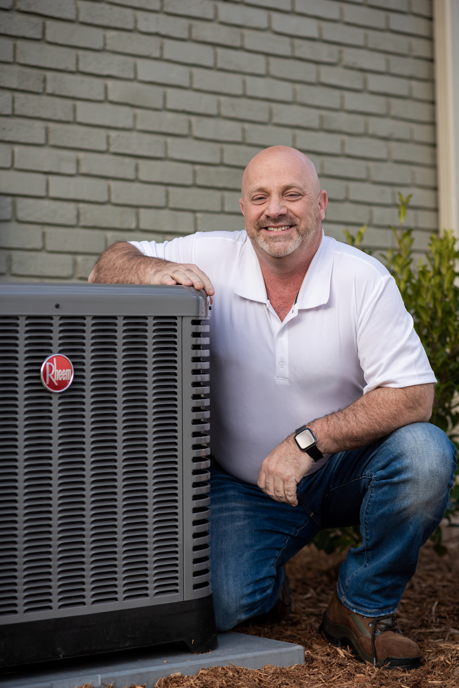 Homeowner kneeling next to Rheem AC unit