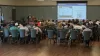 An audience is looking at and AEC Resources slide on the screen during the presentation