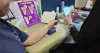 A man is getting a bone screening at a station with a Loss of Bone display showing examples of what bones look like at different stages of bone loss.