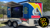 A solar powered mobile charging station trailer - with the county logo on one side, the side door lifted to show a TV, and in the bottom right of the picture is the 50 for 50 logo