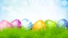 Illustration: Colorful Easter eggs in the grass against a bright blue sky