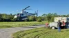 A helicopter hovers near the ground next to the mosquito control truck.