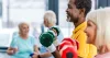 A senior man and woman using dumbbell weights in a gym