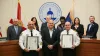 Two Firefighters stand next to Commissioner Boles in front of the dais with the rest of the County Commissioners standing behind the dais