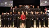 15 recruit firefighters in dress uniform are on stage with the Fire Chief, Bonnie Wise, and the judge who administered the oath