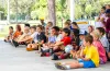 A group of kid and counselors sit on the ground during a camp day at Keystone Park
