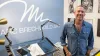 Marc Brechwald standing next to his drawing table and in front of some of his artwork on the walls of his studio