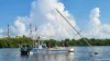 The marine safety unit is looking at a sail rigging sticking up out of the water set against a bright blue sky with clouds.