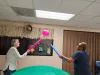 Two women bat at a balloon with foam pool noodles