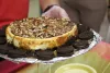 A cheesecake topped with walnuts, caramel and chocolate on a plate surrounded by Oreo cookies