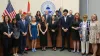 Students and guests stand in front of the dais with the County Commissioners standing behind the dais