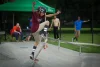 A young kid is doing a trick on his skateboard with people in the background watching.