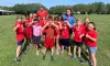 Two summer camp counselors standing with a group of kids