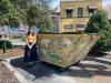 Woman standing next to painted dumpster