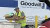 Man loads a box of clothing into a basket in front of the Goodwill Industries-Suncoast truck.