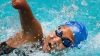 A swimmer who is missing her right forearm rises out of the water during a stroke