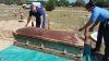 Two men bringing up a coffin from the ground